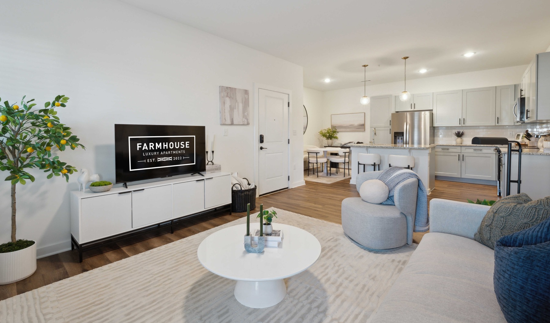 A large living room with seating and an attached kitchen with an island A large living room with seating and an attached kitchen with an island