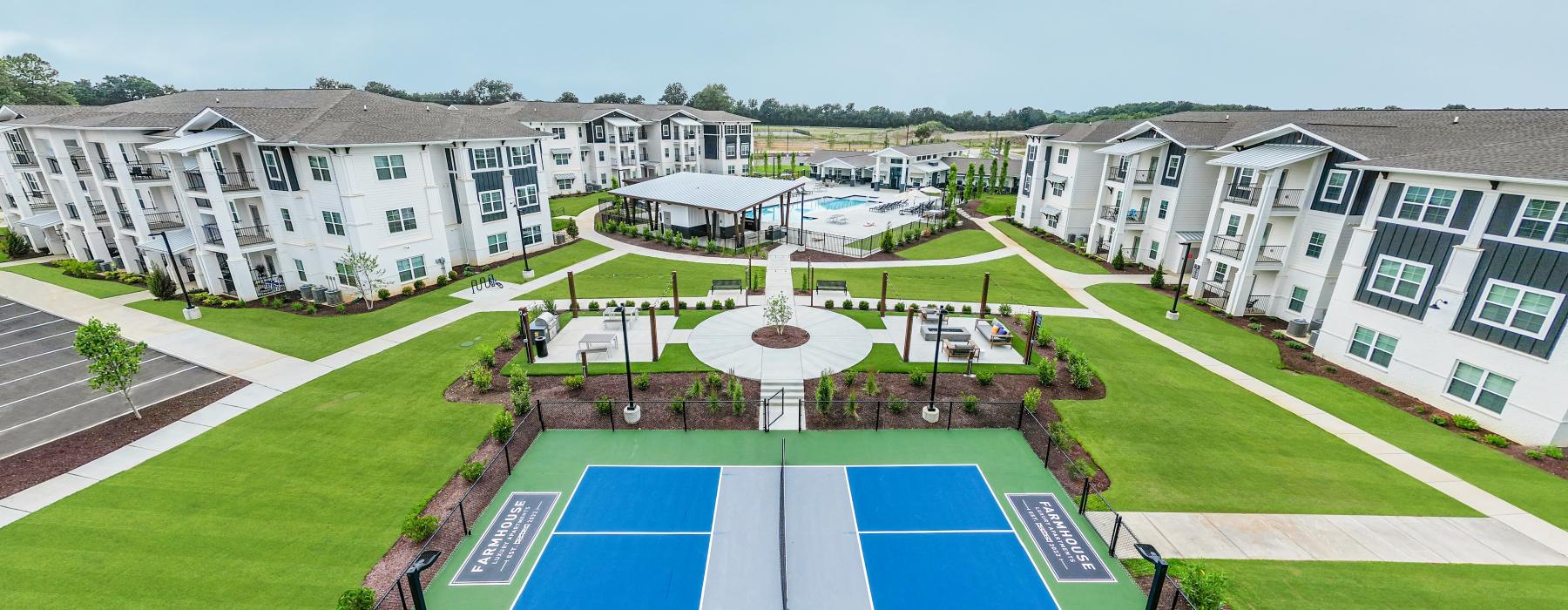 a tennis court in front of a row of white buildings